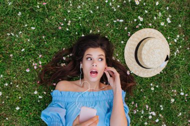 Güzel kadın kulaklık ile müzik dinlerken ve beyaz çiçeklerbir bahçede yalan