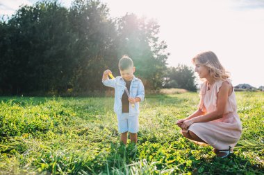 Anne ve küçük oğlu yaz günü açık sabun kabarcıkları üfleme