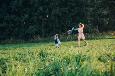 Mutlu aile anne ve çocuk gün batımında doğaya bir uçurtma fırlatın.