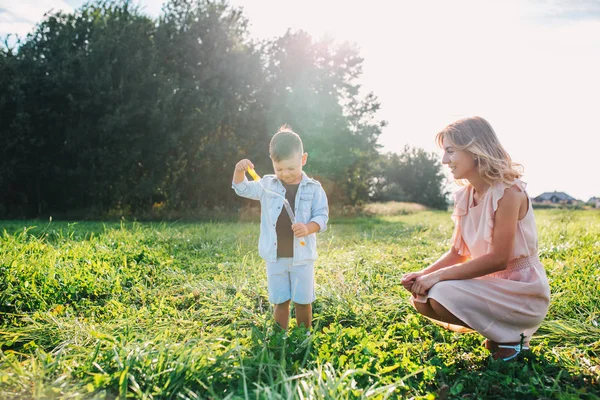 Madre e hijo soplando burbujas de jabón en el día de verano al aire libre — Foto de Stock