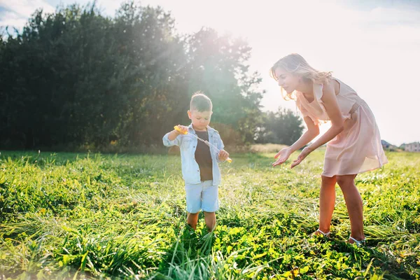 Mamma och Lille son blåser tvål bubblor i sommardag utomhus — Stockfoto