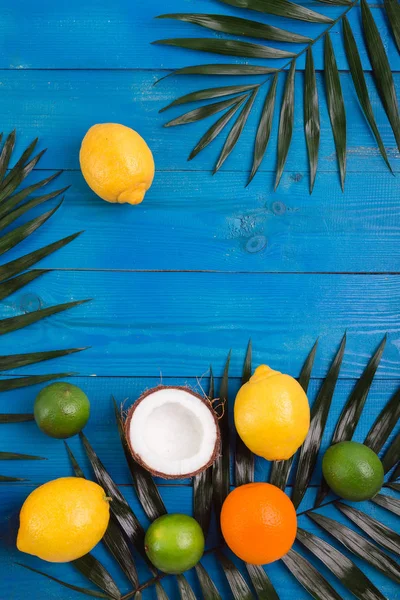 Vários frutos, folhas verdes e flores na mesa de madeira azul. Fundo de verão tropical — Fotografia de Stock