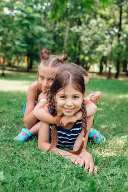 Yaz parkında çimenler üzerinde oynayan üç komik littlle kız