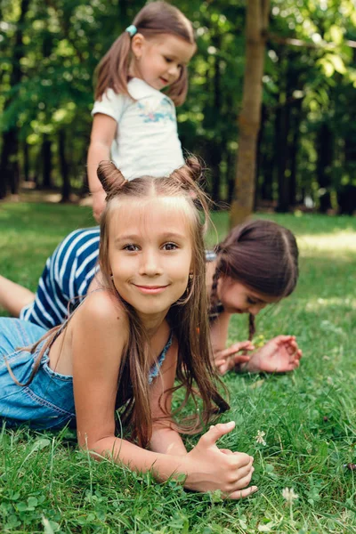 Tre roliga littlle barn som leker på gräset i sommar parken — Stockfoto