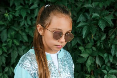 Yazın ya da sonbaharda giyinmiş şık küçük kız çocuğu, açık havada güneş gözlüğü.