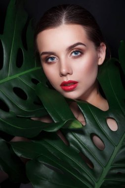 yeşil yaprakları makyaj ve kırmızı dudaklar ile güzel kadın