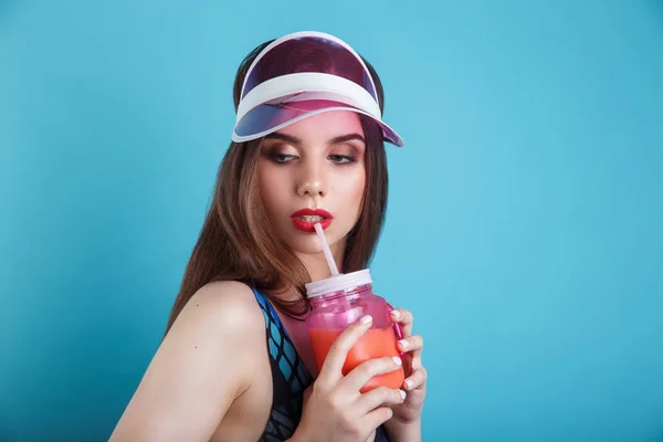 Szexi nő a fürdőruhát és műanyag Visor gazdaság pohár friss nyári ital, kék háttér — Stock Fotó