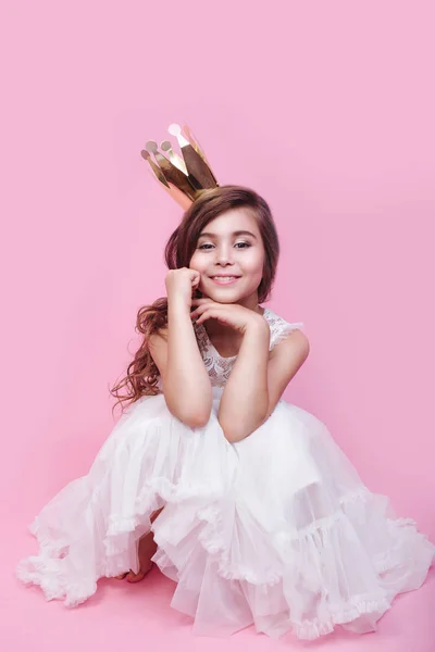 Niña linda princesa en la corona de oro y hermoso vestido sobre fondo rosa — Foto de Stock