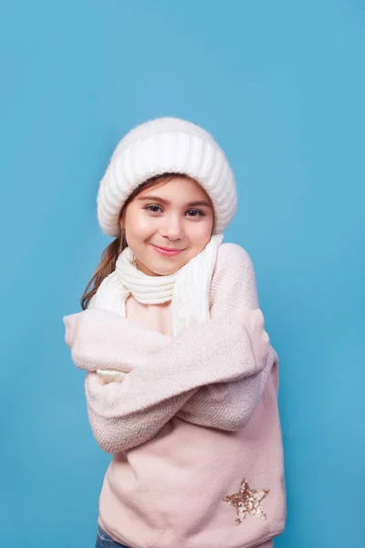 Linda niña con gorra de lana blanca y bufanda sobre fondo azul — Foto de Stock