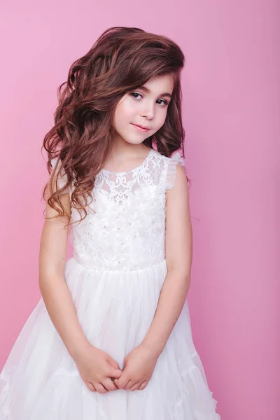Retrato de hermosa niña en vestido blanco sobre fondo rosa — Foto de Stock