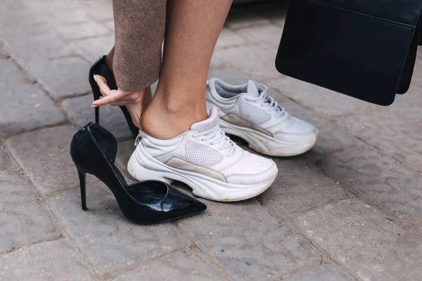 Босоногая деловая женщина, заправляющая туфлями от каблука до удобных кроссовок — стоковое фото