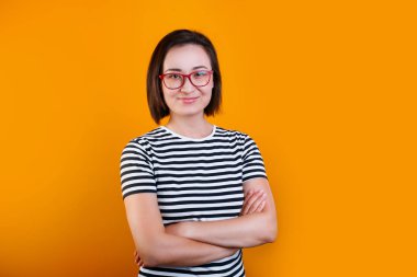 dost asyalı kadın çapraz kolları ile ayakta, bir şey gülüyor, kameraya bakarak.