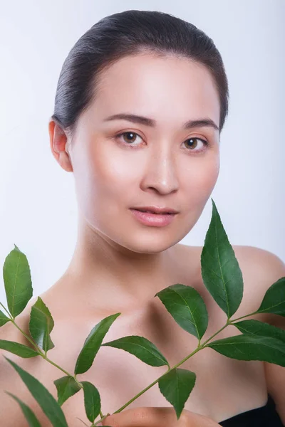 Belle femme asiatique visage portrait avec feuille verte. Concept pour soins de la peau ou cosmétiques bio — Photo