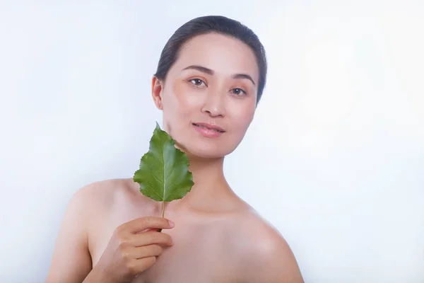 Bella donna asiatica volto ritratto con foglia verde. Concetto per la cura della pelle o cosmetici biologici — Foto Stock