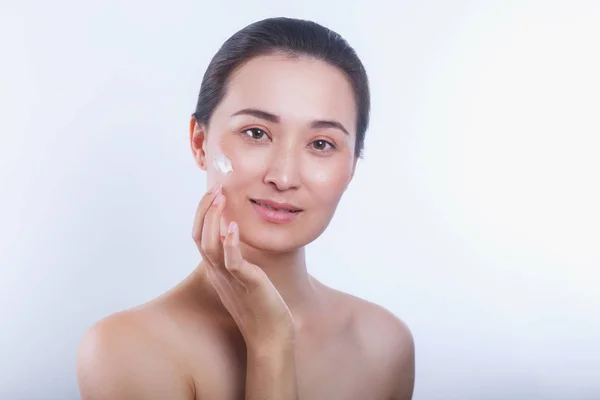 Bela jovem asiático mulher aplicação cosmético creme no seu rosto — Fotografia de Stock
