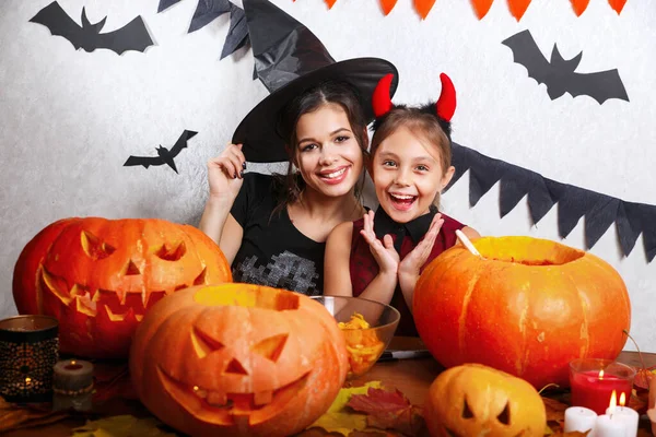 Moeder en dochter plezier thuis. Voorbereiden van Halloween en gelukkige familie. Mensen die dragen carnaval kostuums. — Stockfoto