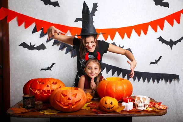 Moeder en dochter plezier thuis. Voorbereiden van Halloween en gelukkige familie. Mensen die dragen carnaval kostuums. — Stockfoto