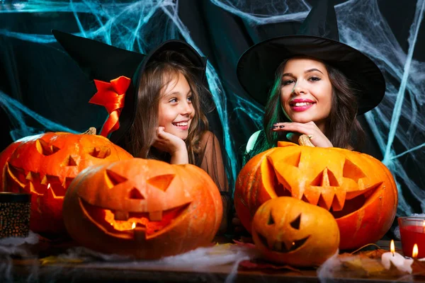 Madre e sua figlia in costume da strega si divertono a casa. Famiglia felice che si prepara per Halloween . — Foto Stock