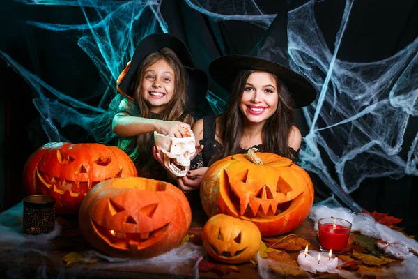 Mutter mit glücklicher kleiner Tochter genießen mit Halloween-Bonbons und Süßigkeiten über Fledermäusen und Spinnennetz auf schwarzem Hintergrund. — Stockfoto