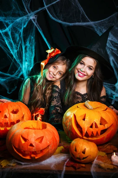 Close-up mooie blanke moeder en haar dochter in heks kostuums vieren Halloween poseren met gebogen pompoenen — Stockfoto