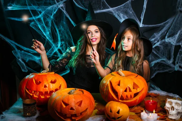 Feliz Dia das Bruxas. Bela mãe caucasiana e sua filha em trajes de bruxa gostam de usar magia com varinha mágica — Fotografia de Stock