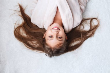 Küçük tatlı kız bornozuyla yatakta yatıyor. Yukarıdan görünüşü