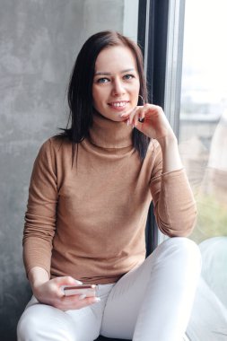 Evde akıllı telefon kullanan genç bir kadın. Evde kal.