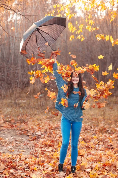 Szczęśliwa kobieta sprawia, że deszcz z liści w jesiennym parku. — Zdjęcie stockowe