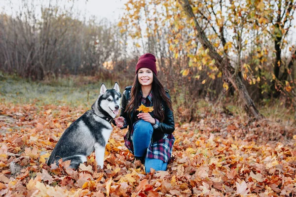 Stylische Hipsterfrau sitzt mit ihrem Husky-Hund im Herbstpark — Stockfoto