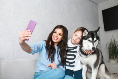 Anne ve küçük oğlu evde köpekle selfie çekiyorlar.