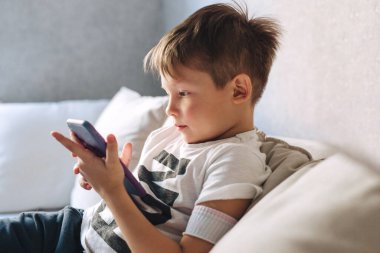 Küçük çocuk kanepede otur ve evdeki telefonu kullan.