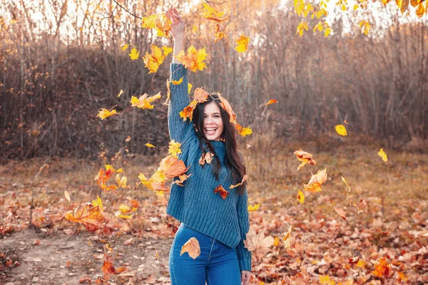 Młoda kobieta bawi się jesiennymi liśćmi w parku. — Zdjęcie stockowe