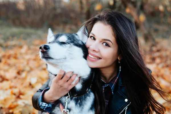 Mulher feliz abraçando seu cão husky no parque de outono. — Fotografia de Stock