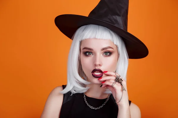 Halloween sexy heks portret met donkere lippen en wit haar op oranje achtergrond. — Stockfoto