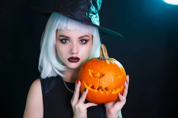 Bruja sexy de Halloween con una calabaza tallada sobre fondo oscuro — Foto de Stock