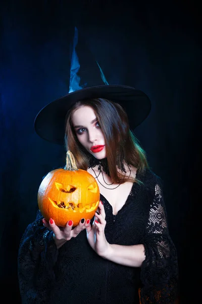 Fijne Halloween. Halloween heks met een magische pompoen op zwarte achtergrond. — Stockfoto