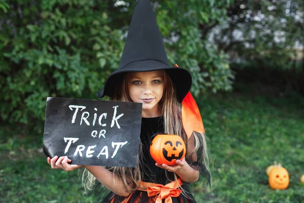 Klein meisje in heksenkostuum truc of traktatie buiten. Gelukkige Halloween — Stockfoto