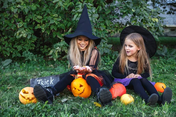 Komik küçük kızlar Cadılar Bayramı 'nı kutluyor ve şeker yiyorlar. — Stok fotoğraf