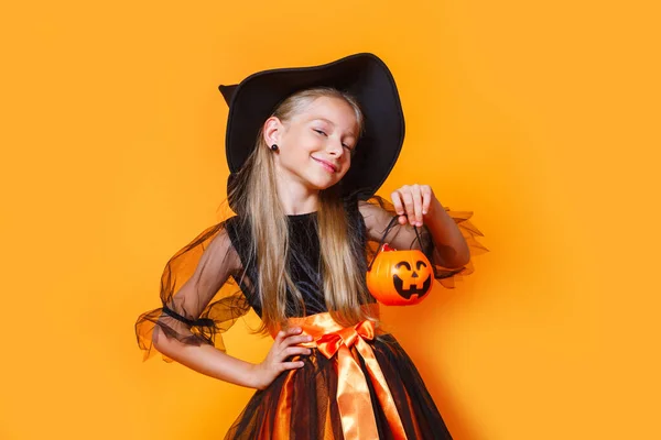 Schattig meisje in Halloween wicth kostuum op oranje achtergrond — Stockfoto