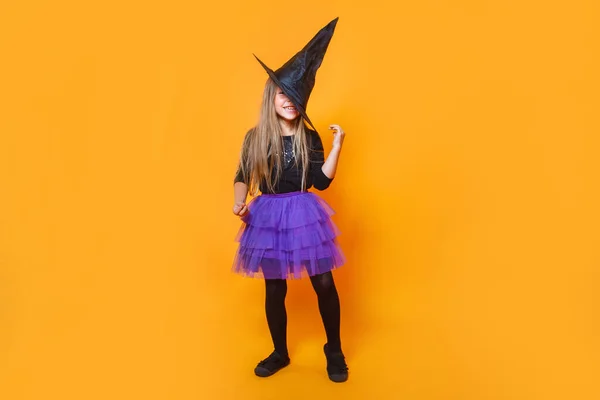 Смешная девушка в костюме ведьмы на оранжевом фоне — стоковое фото