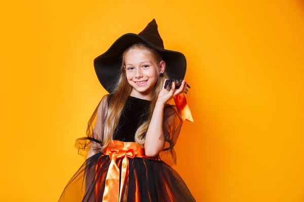 Meisje in Halloween wicth kostuum op oranje achtergrond — Stockfoto