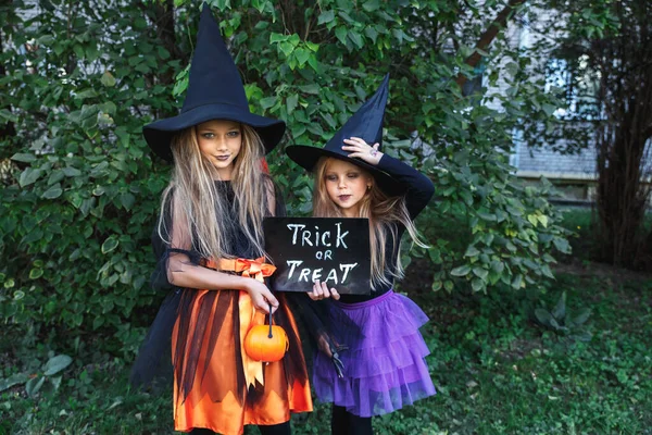 Dvě holčičky v kostýmech čarodějnic se baví o Halloweenu. Trick or treat — Stock fotografie