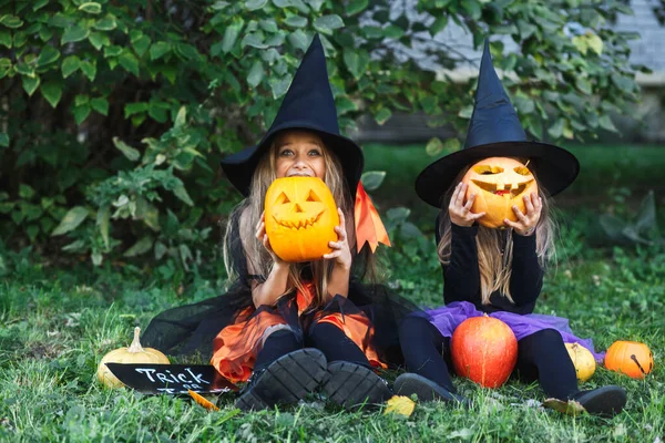 Wesołego Halloween. Dwoje zabawnych dzieci w kombinezonach czarownic i z dyniami w lesie — Zdjęcie stockowe