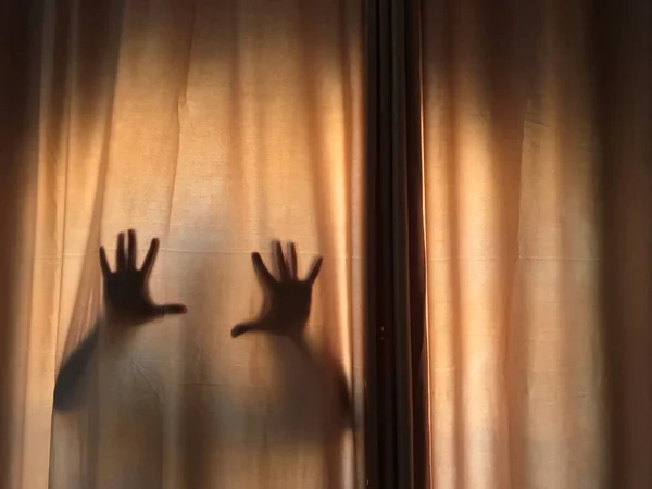Horror scene of blurry shadow of hands behind curtains, in a spooky way, Halloween Horror night. With space on the right for text. Copy space.