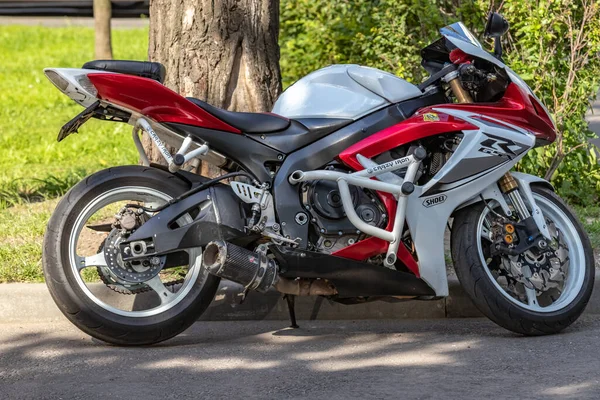 Park yerinde bir ağacın altında kırmızı Suzuki Motosikleti. Kapat..
