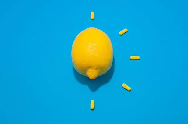 Bir sarı limon ve mavi arka planda beş hap.