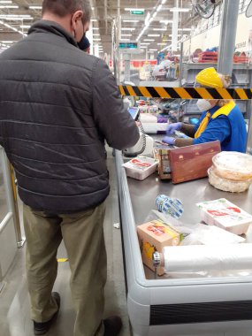 Lenta hipermarketinde, koronavirüs enfeksiyonu yayılırken maskeli bir adam kasada ödeme yapar.. 