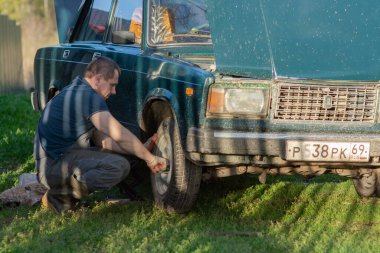 Bir adam arabanın tekerleğini değiştirir..