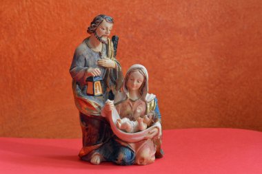 Doğum sahnesi. İsa, Meryem ve Yusuf heykelcikleri turuncu arka planda 