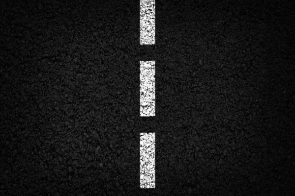 Single white dashed line on black asphalt background